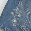 Ultra lav midje, medium vasket, blomsterbrodert denim minishorts
