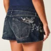 Ultra lavt sittende mørkvaskede minishorts i denim med brodert sommerfugl